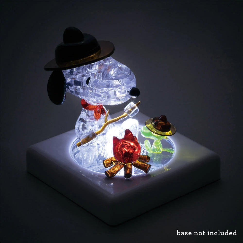 The Snoopy Camp 3D Crystal Puzzle by Snoopy is a charming figurine of a cartoon dog enjoying a delightful camping moment, complete with an LED light illuminating Snoopy by the campfire, cup nearby, and hat on head. Square base not included.