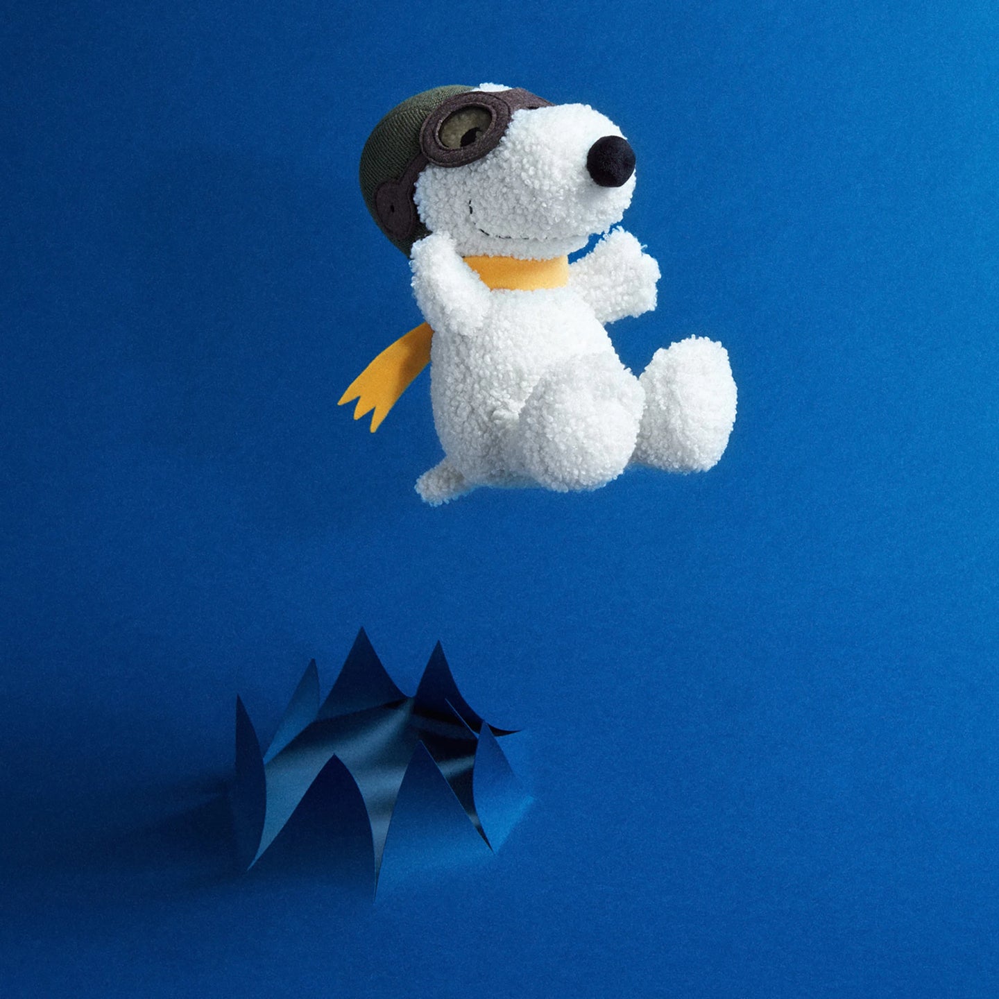 White plush dog with brown pilot goggles and yellow scarf, standing with side pose.