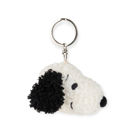 The Snoopy Head Keychain 4.5cm - Soft Terry by Snoopy is made from recycled polyester and features a terrycloth fabric design in the shape of a dog's head. It showcases a white face, black ears, and a black nose, along with a metal loop for convenient attachment.