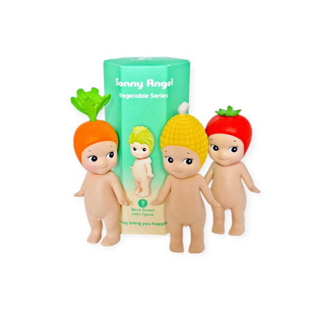 In front of a green box labeled "Sonny Angel Vegetable Series Blind Box," three adorable minifigures wearing hats inspired by a carrot, corn, and tomato stand proudly. Enjoy the thrill of discovering this charming blind box collection from Sonny Angel!