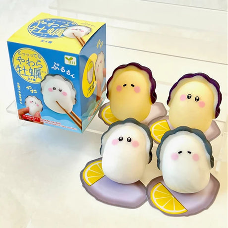 Four cute Squishy Oyster toys with lemon slices and a blue-yellow box in the background on a white surface