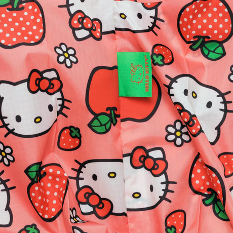 The Baggu Standard Bag - Hello Kitty Apple by Baggu showcases a charming eco-friendly design with a delightful pattern of strawberries and cute apples against a pink background, accentuated by a green tag. Crafted from recycled materials, this sustainable bag is both stylish and environmentally conscious.