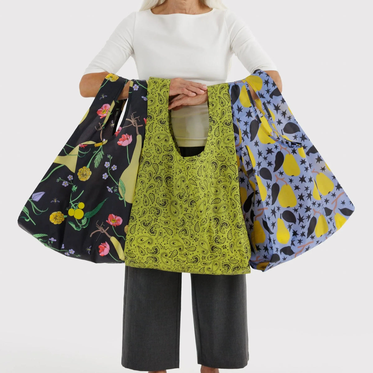 Baggu set of reusable tote bags, floral and paisley patterns held for display