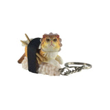 Introducing the Sushi Cat Keychain Blind Box - Vol.2 by Mofusand, a delightful accessory showcasing a small lizard dressed whimsically in a frilled hat and carrying a strap. This unique piece pairs perfectly with your collectible Sushi Cats, bringing an extra touch of charm to your cherished collection.