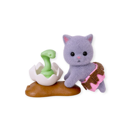 Purple-gray cat figurine with pink scarf, sitting on brown cushion with egg
