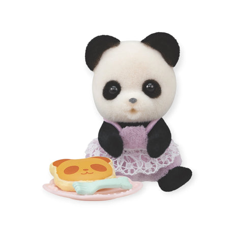 A cuddly panda toy dressed in a purple outfit is placed alongside a dish featuring a panda-shaped pancake and cutlery, capturing the whimsical essence of the Sylvanian Families Blind Bag - Baby Treats Series by Sylvanian Families.