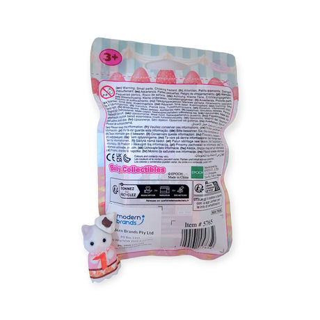 A small cat figurine sits next to a bag with printed information, including safety warnings and supplier details. The bag is labeled as "Sylvanian Families Blind Bag - Baking Baby Party," perfect for those who treasure collectible critters.