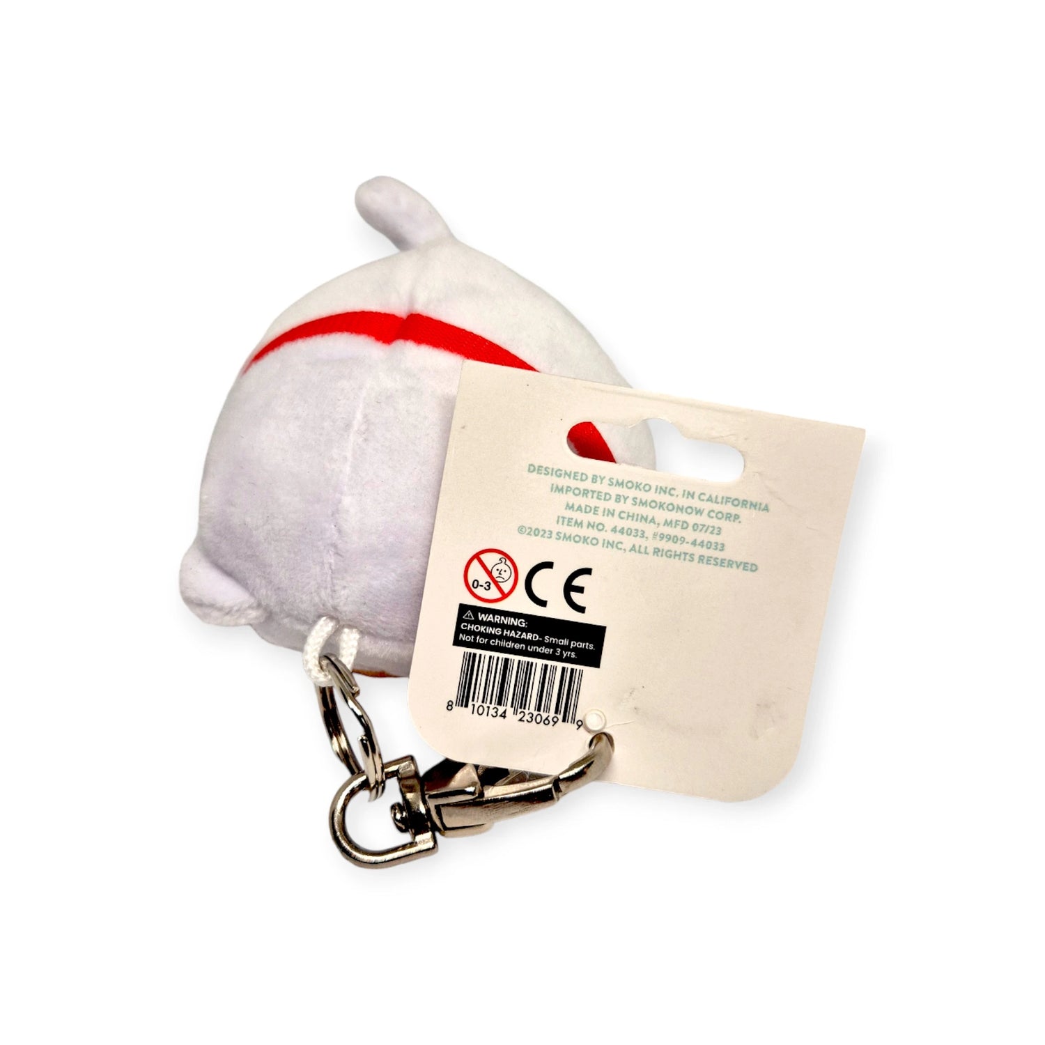 This charming Smoko Tayto Potato Lucky Cat Keychain Plushie is a small, round white plush keychain with a red stripe and a metal clip, making it both an adorable accessory and a good luck charm. It comes with an attached tag displaying product information, making it an ideal addition to your collection.