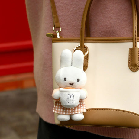 White rabbit plush keychain with a bunny patch, hanging from a beige handbag