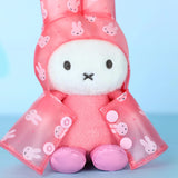 Close-up of pink plush rabbit raincoat keychain with white face and bunny print