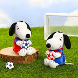 Snoopy soccer plush keychain on grass holding a blue-and-white soccer ball