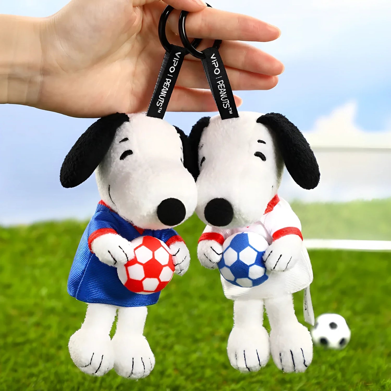 Two Snoopy soccer plush keychains in blue and red jerseys with soccer balls