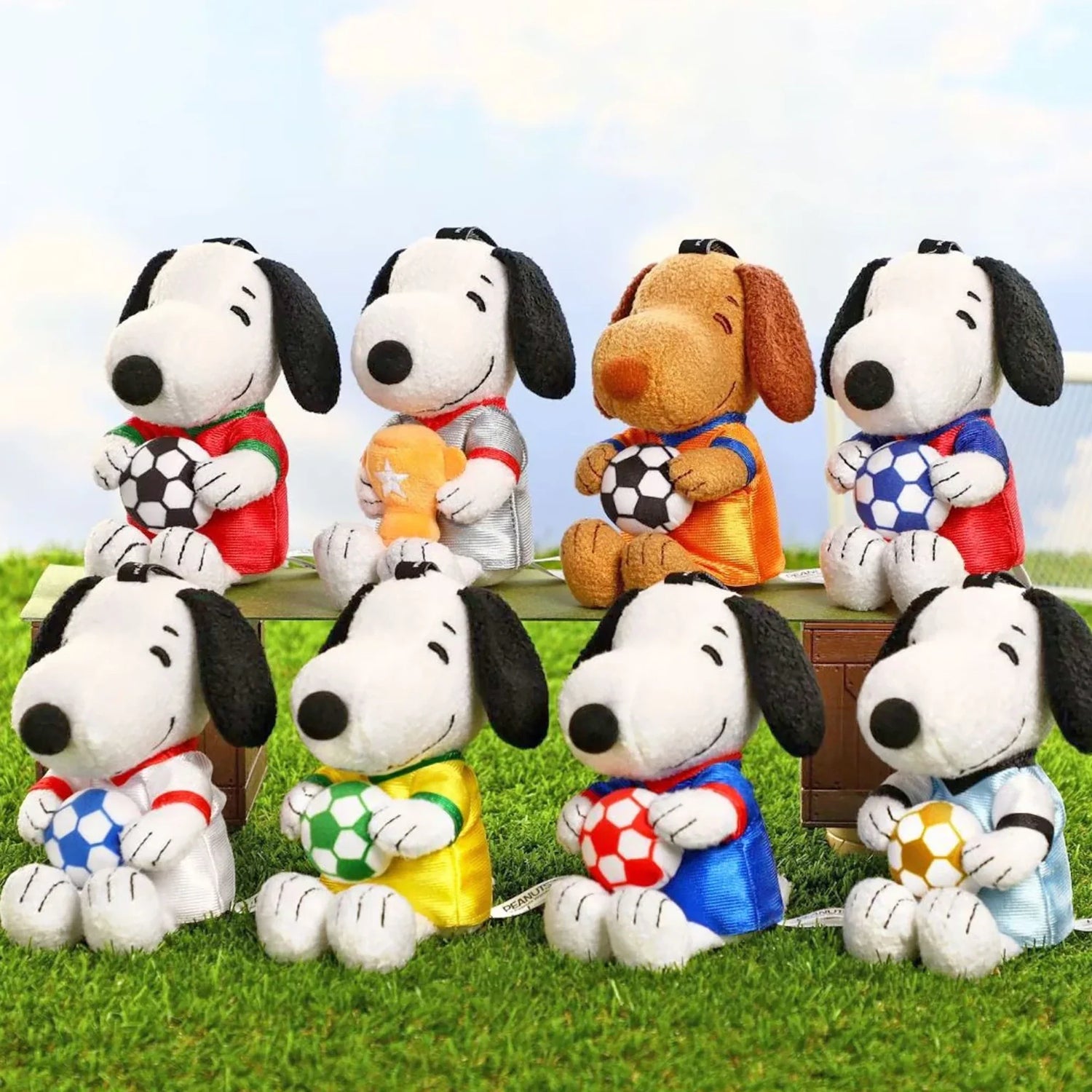 Assorted Snoopy soccer plush keychains with different jerseys, each holding a soccer ball