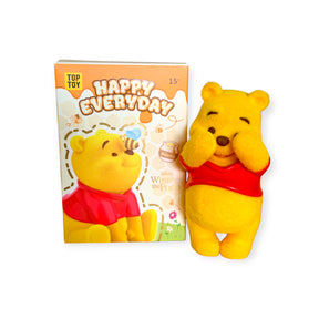 Small plush bear in red shirt covering eyes, beside colorful box with bear and "Happy Everyday" text