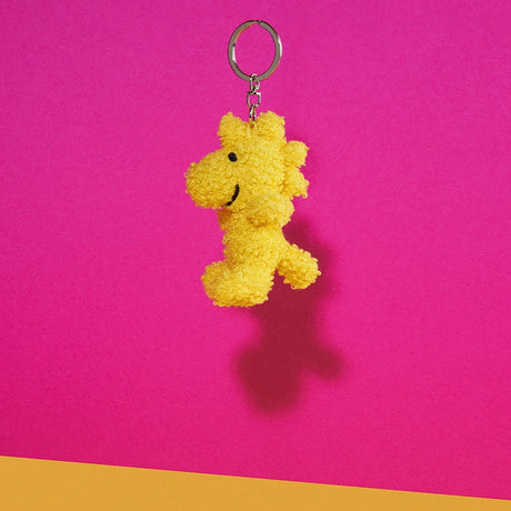 Brighten your day with the Snoopy Woodstock Keychain 7cm, a charming Terry plush shaped like Woodstock from Peanuts™, featuring a vibrant pink and yellow backdrop.