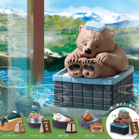 Brown bear figure relaxing in onsen tub with towel on head, set against mountain and water backdrop, gallery 1