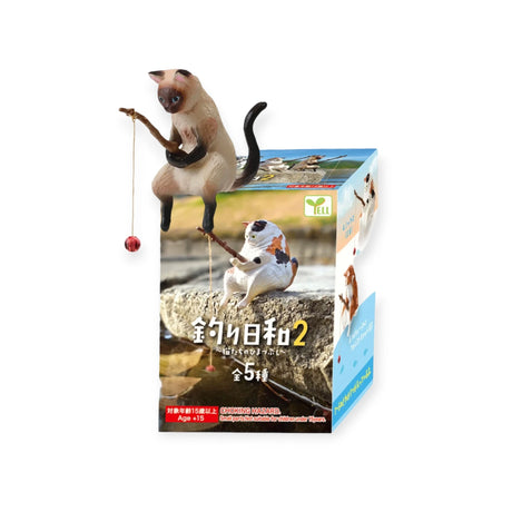 The Fishing Cats Blind Box - Vol 2 by Yell features an illustrated cat angler with a fishing rod on a rock, ideal for collectors and cat lovers. Text and logos are in Japanese.