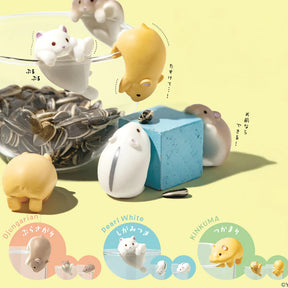 Yell's Wobble Cup Hamster Blind Box features miniature hamsters—Djugarian, Pearl White, and KINKUMA—interacting with a glass of sunflower seeds and a blue cube. Each is labeled and makes an adorable desk toy.