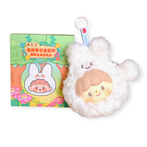 Fluffy white plush keychain with a smiling face inside and attached to a colorful illustrated green and orange box